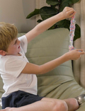 A child stretching colourful Crazy Aaron's Thinking Putty from The Play Way's therapist-designed regulation kit.