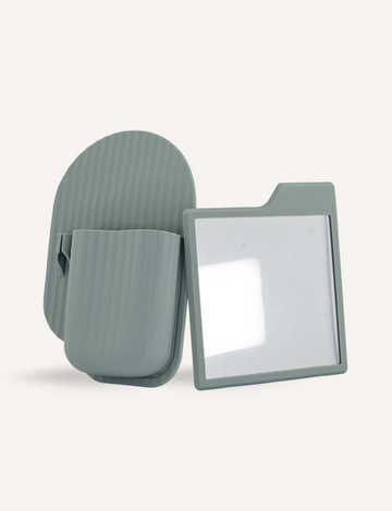 The Sensory Play Australia's Bathroom Organiser and Shower Mirror in gray features a textured case with a matching lid, opening to reveal a rectangular, semi-transparent sheet with a tab on the top-right corner. Ideal for enhancing self-care routines, its plain light background adds serenity.