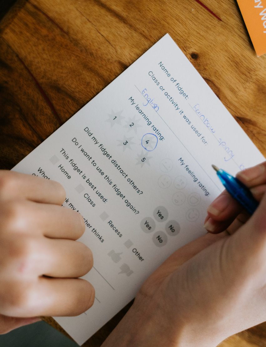 A close-up of hands completing a worksheet from The Play Way's Reflection Kit, aiding children in emotional processing and self-awareness.