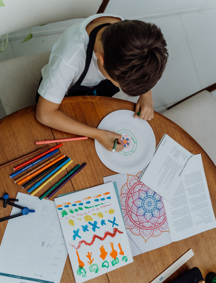 The Creative Mindfulness: Mandalas Program by Therapy At Home features a vibrant box with art supplies for kids—colored pencils, markers, paints, rulers, paper, and a "The Play Way" tote—ideal for fostering creativity and fine motor skills.