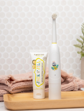 White Jack N' Jill buzzy electric toothbrush and flavor-free toothpaste on a wooden tray.