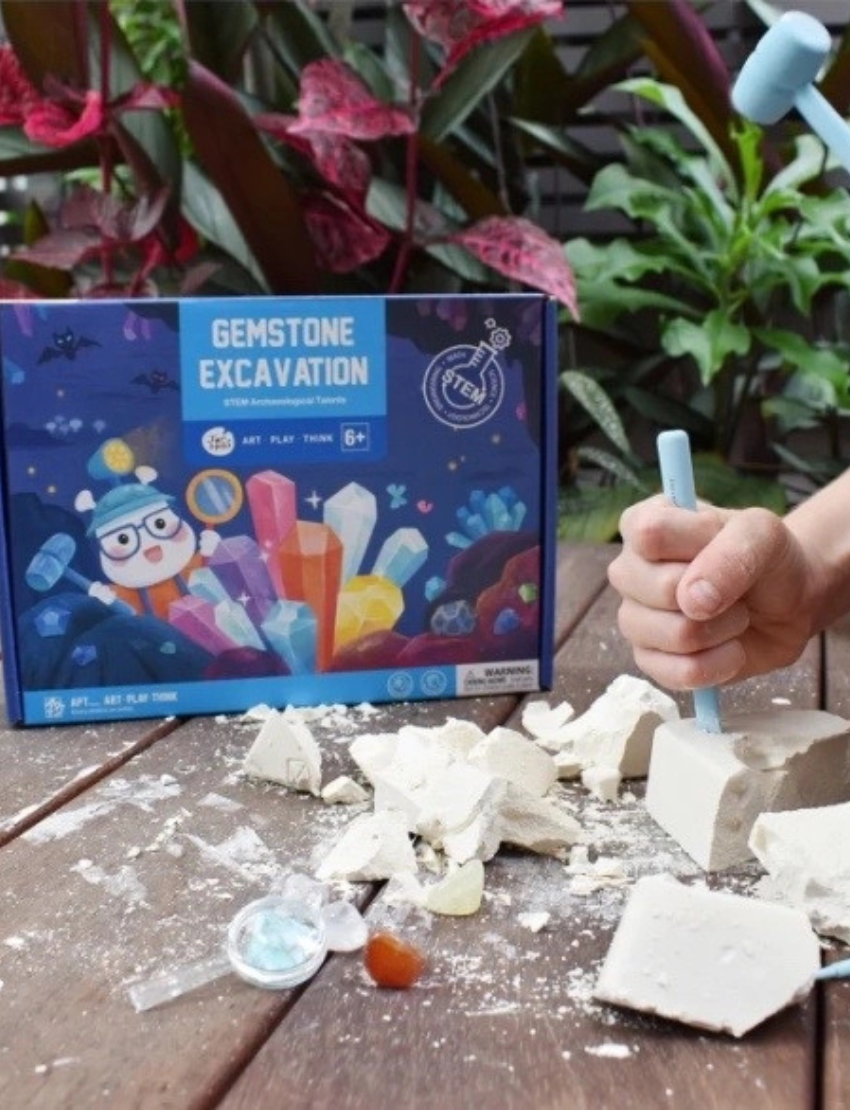 The Play Way Gemstone Excavation STEM kit box, featuring a colorful illustration of gems and tools for aspiring geologists.