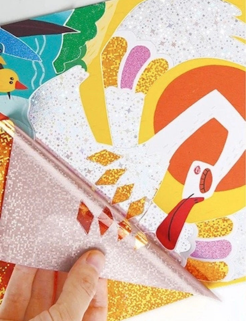 Close-up of a hand applying shimmering glitter stickers to a 'The Ugly Duckling' flash sticker artwork.
