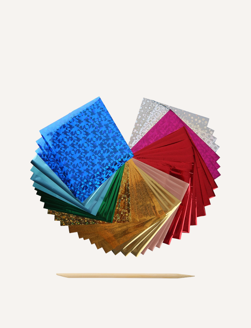 Collection of colorful holographic and glitter sticker sheets arranged in a fan shape, with a wooden tool.