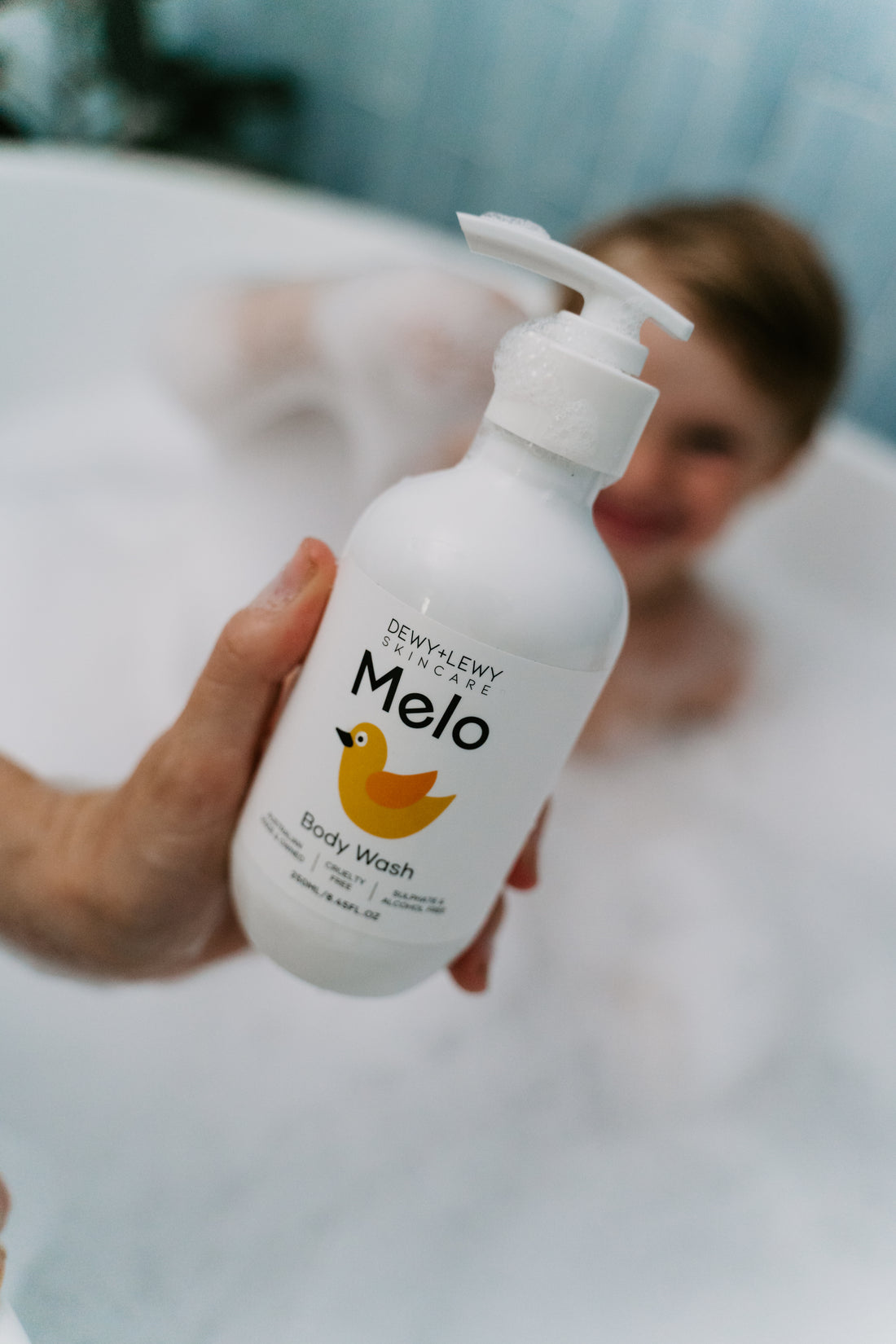 Two white pump bottles of Melo Body Wash and Lotion by Dewy+ Lewy are in an open box.