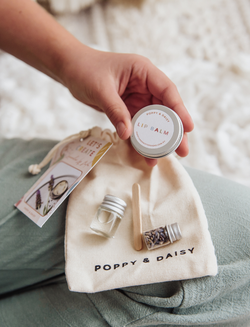 Poppy & Daisy Lavender Lip Balm DIY Kit: includes ingredients, tin, craft cup, and drawstring bag for making balm.