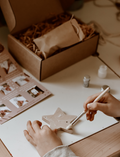 Child's hands painting a wooden star shape for a DIY decoration kit.