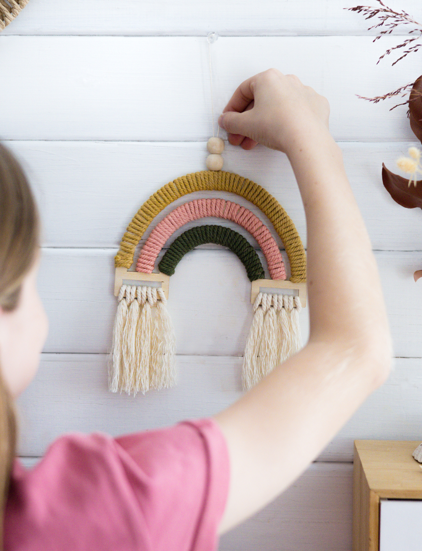 Poppy & Daisy Macrame Rainbow DIY Kit: includes cardboard box, wooden rainbow shape, yarn, beads, and instructions.