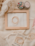 Overhead view of a wooden frame and beads from the Poppy & Daisy Friendship Necklaces kit.