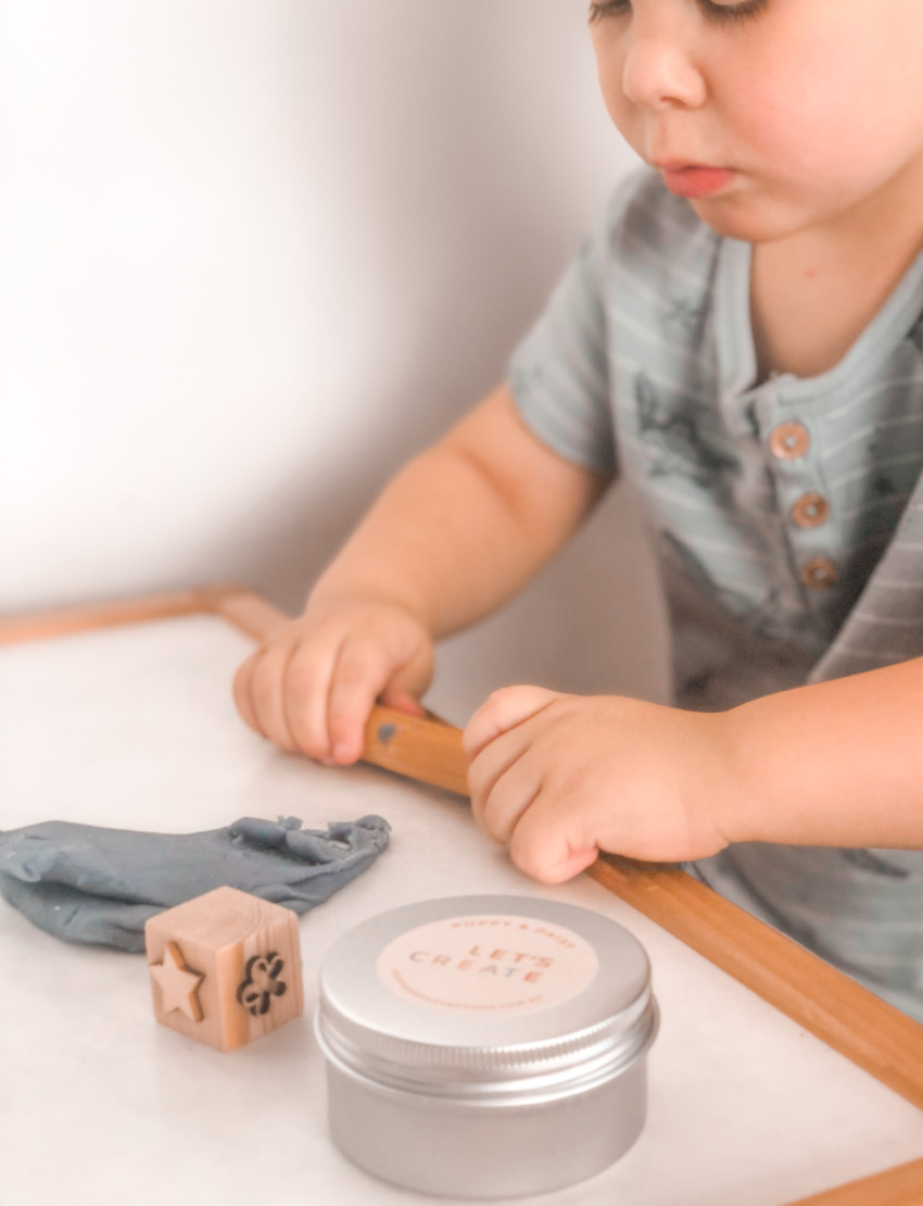 Child using Poppy & Daisy natural playdough with wooden stamps and cookie cutters.