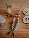 Beaded strings with wooden bag tags (heart, butterfly) and DIY supplies on a wooden surface.