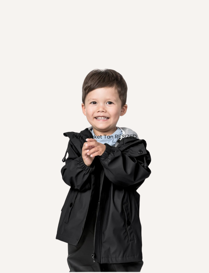A smiling young boy wearing a black rain jacket and a grey hood, isolated on a pale background.