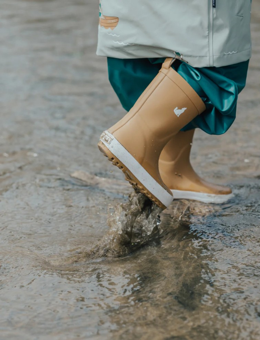 Pair of tan children's rain boots with white soles and wolf logo, presented on a light background.