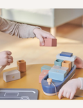 Children's hands playing with a wooden ship toy and colorful blocks. Montessori-inspired stacking toy for toddlers.
