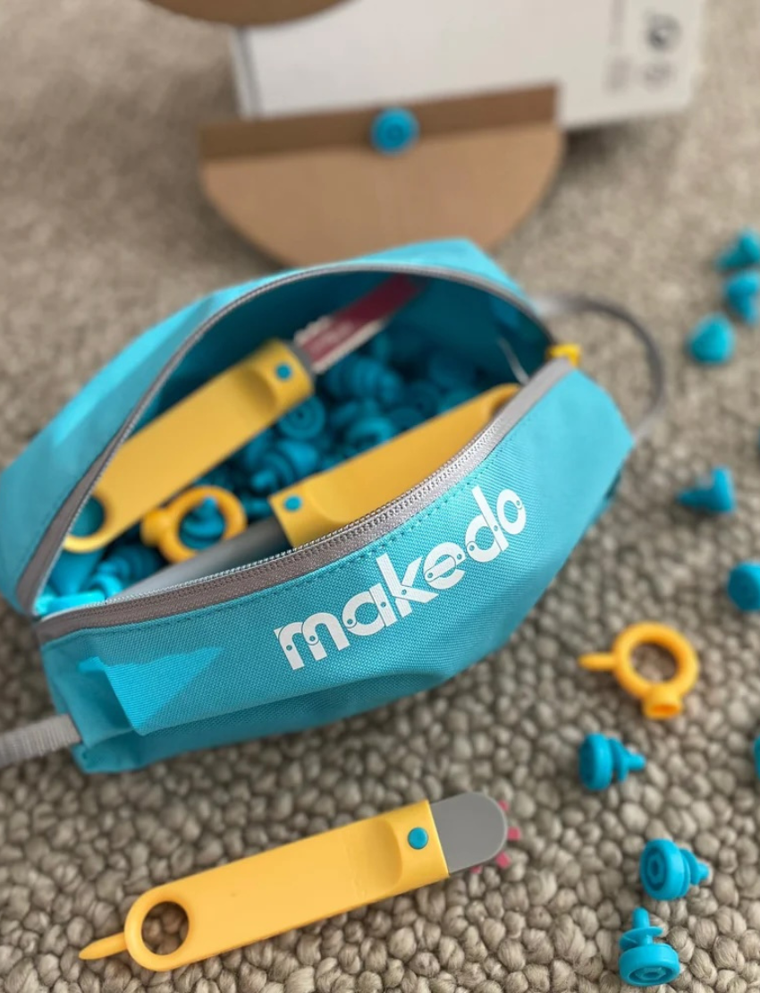 Makedo blue tool case with yellow zipper, on a plain light grey background.