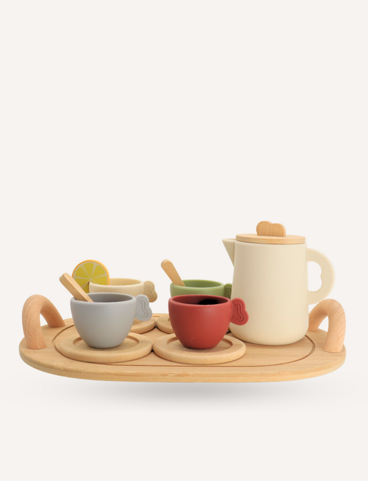 A child indulges in imaginative play with Sensory Play Australia's wooden Teatime Set, featuring a tray, three cups, a teapot, and spoons. Nearby is a metal sink with a draining area on the countertop to enhance cognitive skills through interactive fun.