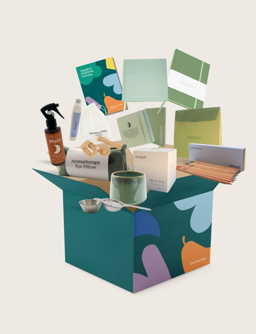 The Therapy At Home Caregiver Wellbeing Training Program includes a ceramic mug, bath salts, aromatherapy eye pillow, tea, notepads, colored pencils, and booklets—perfect for supporting caregiver wellbeing and emotional regulation.