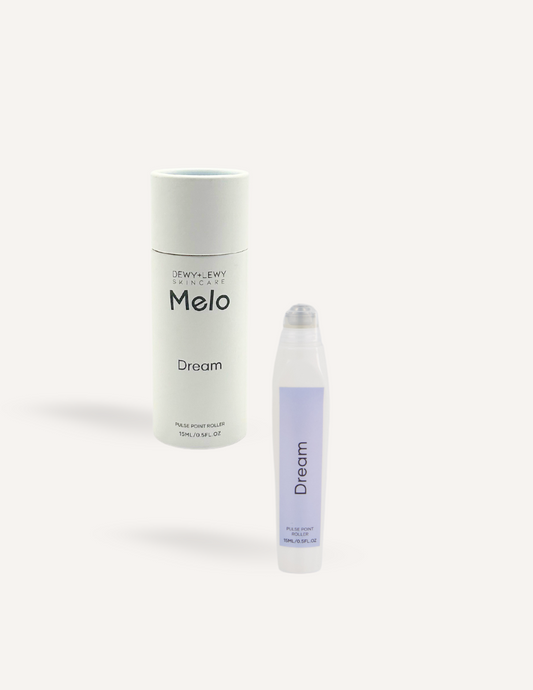 A cylindrical container labeled "Melo Dream" sits beside a small oil roller bottle with a purple label that reads "Melo Pulse Point Oil Roller - Dream." Both items, ideal for a calming bedtime ritual with essential oils, are set against a plain white background.