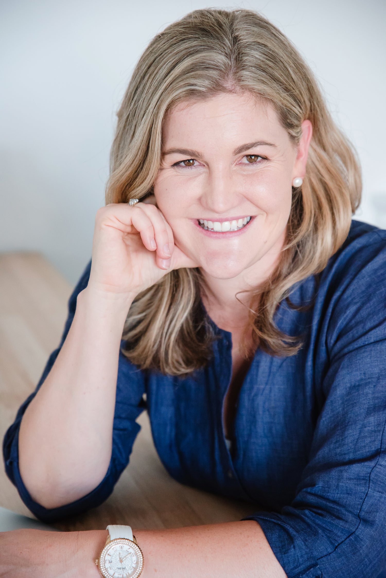 Headshot of Kait Cummins resting her chin on her hand, smiling warmly.