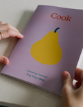 A notebook with a lavender cover featuring an illustration of a yellow pear at its center. The word 