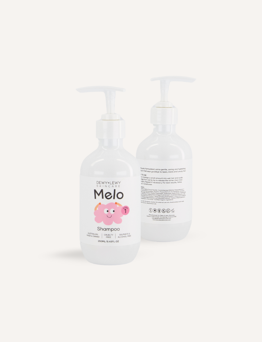 A teal box adorned with colorful shapes opened to reveal the Melo Self-Care Starter Kit by The Play Way, featuring body lotion, body wash, shampoo, conditioner, and detangling spray. Each item is packaged in a white bottle with various illustrations and labeled "Melo.