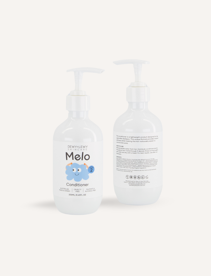 A teal box adorned with colorful shapes opened to reveal the Melo Self-Care Starter Kit by The Play Way, featuring body lotion, body wash, shampoo, conditioner, and detangling spray. Each item is packaged in a white bottle with various illustrations and labeled "Melo.