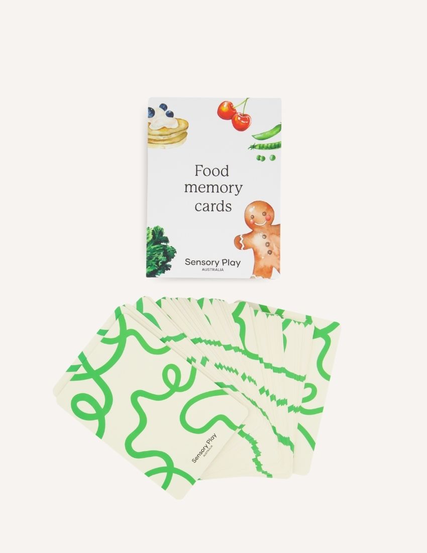 Two Sensory Play Australia "Food Memory Cards Set in Box" packages are shown. The front box displays vibrant illustrations of food items such as broccoli, a gingerbread cookie, and a pie. The back box includes instructions and game information in text and graphics, enhancing the mealtime experience through playful exploration of food.