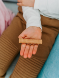 A set of three Wooden Fidgets by Sensory Play Australia is displayed on a white background. The fidgets include a grooved roller, a ring, and a geometric puzzle designed for tactile play and sensory regulation. They are placed on a white drawstring bag labeled 