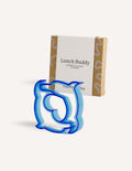 A blue dolphin-shaped sandwich cutter sits in front of a small brown and white box labeled 