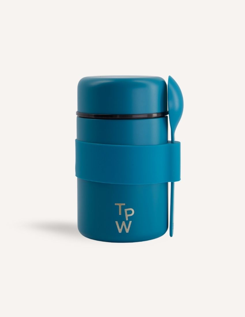 A blue insulated food jar from The Play Way with the initials "T P W" printed on the front. The Lunch Buddy Insulated Container Set features a matching blue silicone band around its midsection that holds a blue spoon, along with a leak-proof lid. The background is plain white.