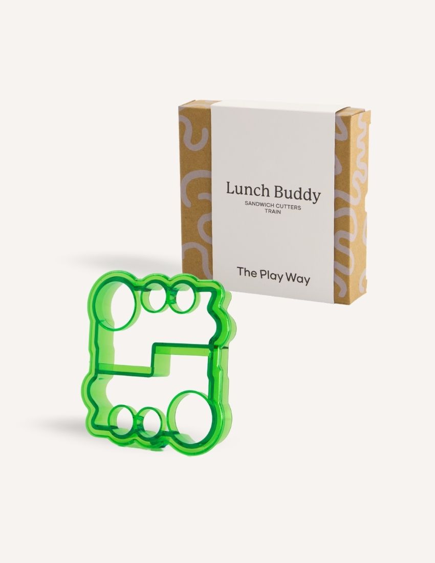 A blue dolphin-shaped sandwich cutter sits in front of a small brown and white box labeled "Lunch Buddy Sandwich Cutters Set" by The Play Way. The box, adorned with wave patterns on the sides, promises fun sandwich shapes designed to delight even the pickiest eaters.