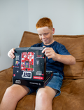 The STEM Adventure - Bit Game Console by CircuitMess is a compact handheld device with a transparent casing, showcasing red components. It includes a small screen, several white buttons, and the 