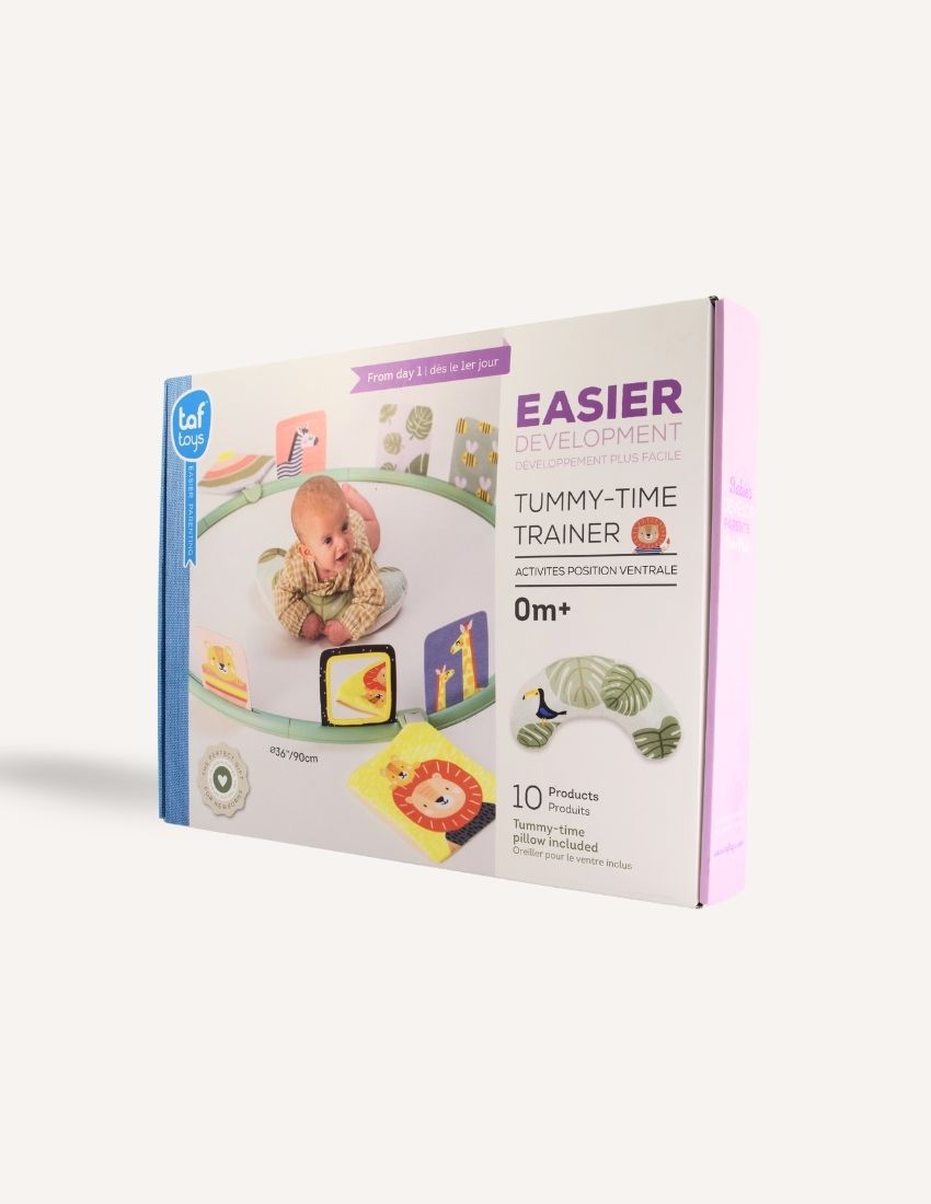 The image showcases the packaging of the "Tummy Time Trainer." The box is primarily white and purple, adorned with images of a baby using the product and featuring a baby-safe mirror. It states "Easier Development" and includes "10 Products" suitable for babies from 0 months old. The brand is TAF.