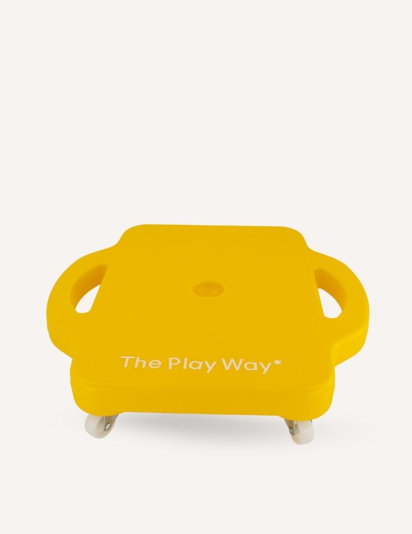 A square yellow plastic "Scooter Board" by The Play Way, featuring two built-in handles on either side and four wheels underneath. The text "The Play Way" is printed on the top surface against a plain white background.