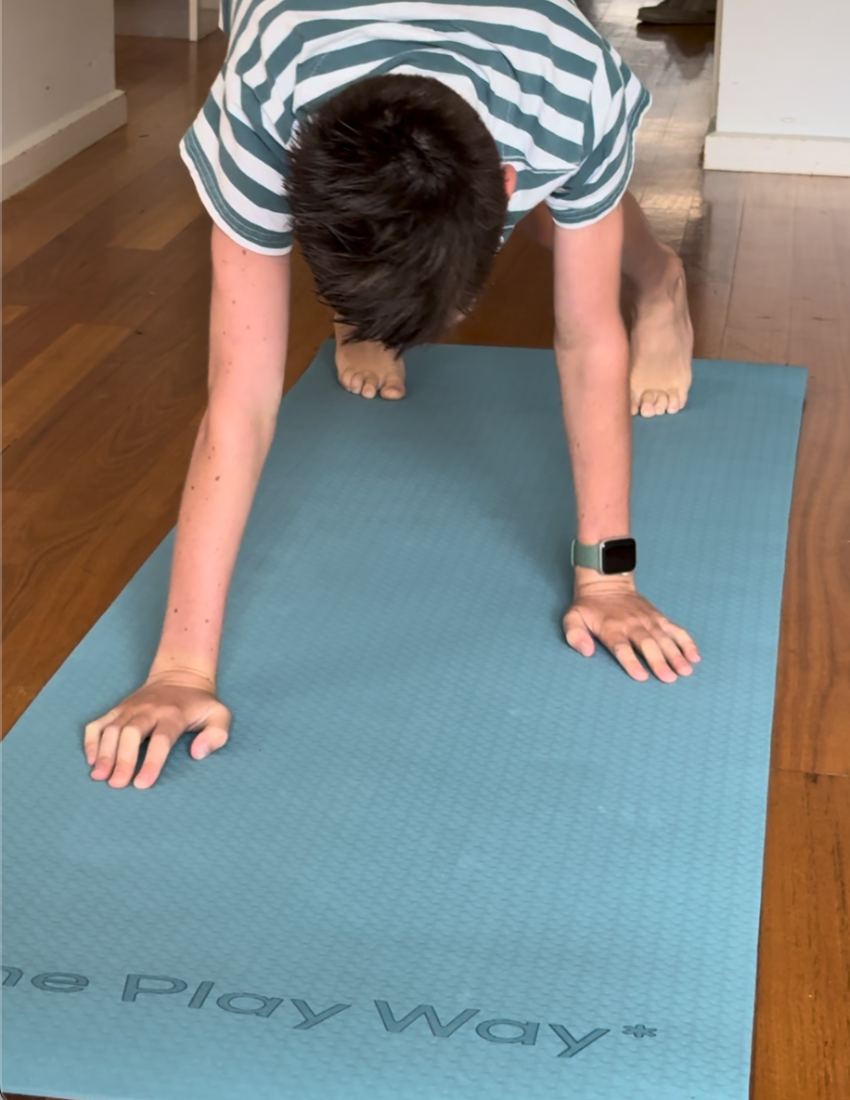 The image shows "Yoga Mat and Cards" by The Play Way, featuring an open box with a teal mat that has a black strap, a Yoga Card Set with animals like lion and elephant, mindfulness text cards, all in a box decorated with colorful abstract shapes.