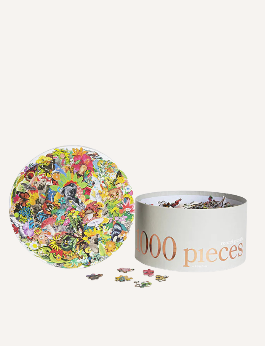 A cylindrical box labeled "1000 pieces" from Journey of Something is open, revealing scattered puzzle pieces. The box showcases a vibrant abstract design centered on a horse, suggesting the challenge of assembling this intricate 1000-Piece Round Puzzle.