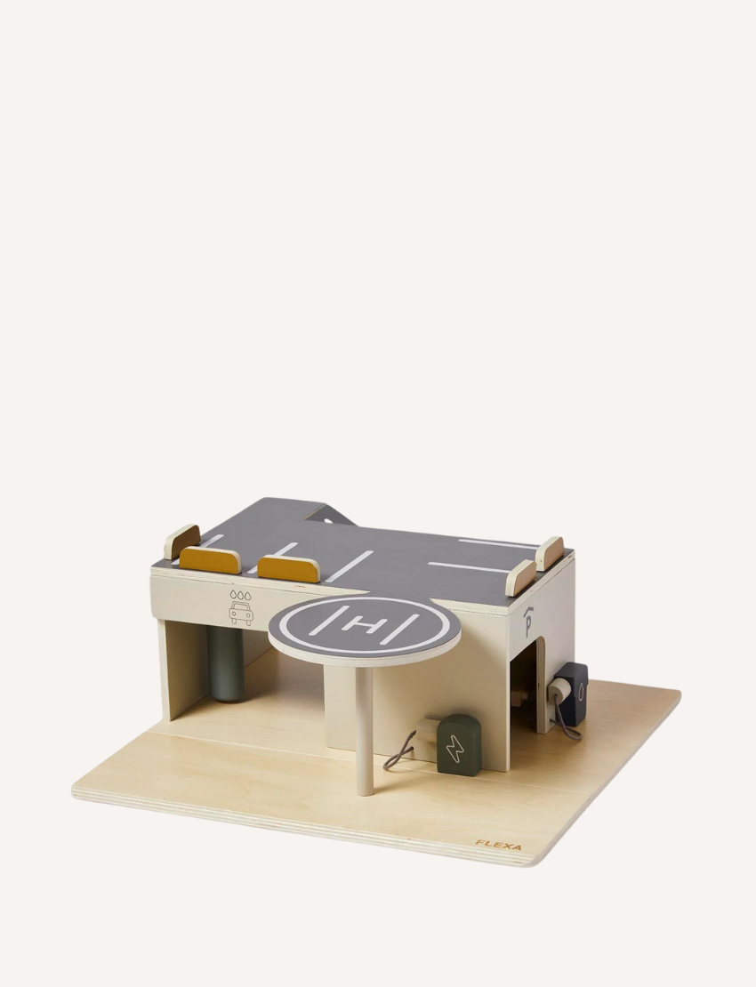 Wooden toy parking garage with helipad and charging station on a light wood base.
