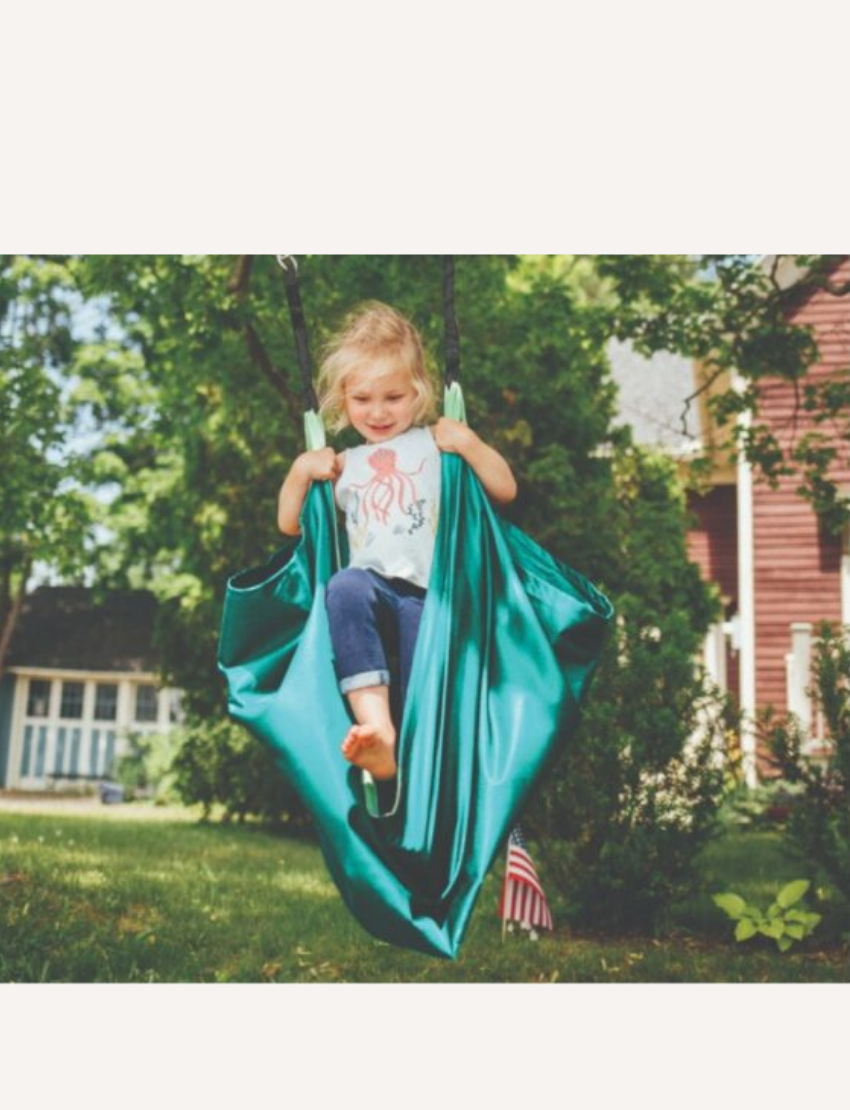 Box of a Slackers Hammock Swing, showcasing an image of a child enjoying the swing. The text on the box emphasizes that this product is a comfortable enhancement for backyard activities, allowing kids to sit, relax, or stand and spin. Suitable for ages 3 and up.