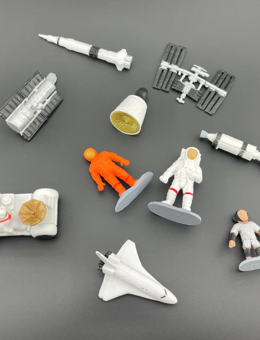 The "Space Toob" by Safari features a collection of small figurines with astronaut and space themes, including astronauts, a space shuttle, a rover, a satellite, rockets, and the International Space Station.