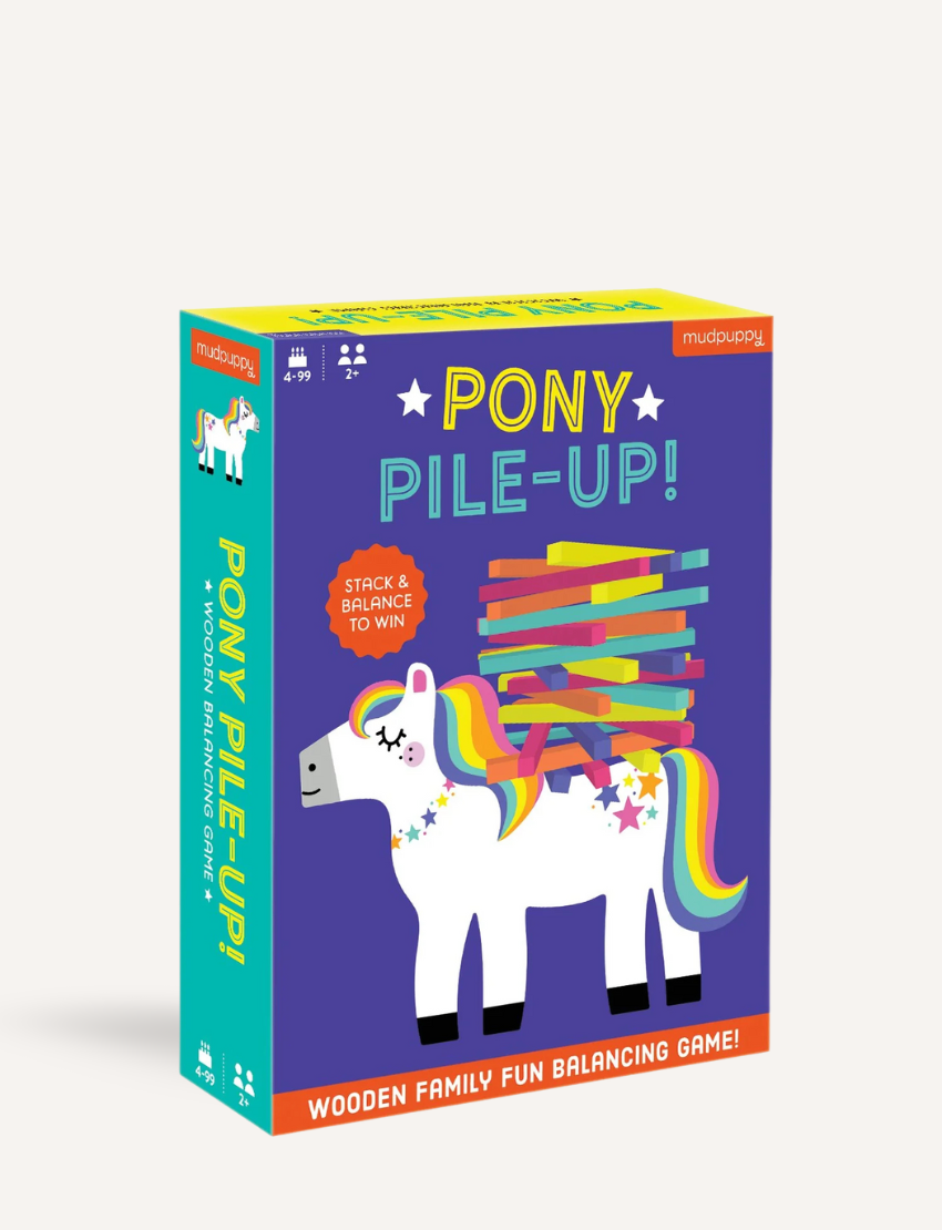 A vibrant box of the "Pony Pile Up Balancing Game" by Mudpuppy, showcasing an illustration of a white pony with a rainbow mane and tail. The pony's back is piled with colorful sticks. The text on the box reads "Stack & Balance To Win" and "Wooden Family Fun Balancing Game.