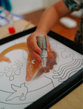 The Therapy At Home Fine Motor Intermediate Program is an open teal box with abstract designs featuring craft and activity sets to strengthen fine motor skills using reusable stickers, sand art, air-dry clay, glue, and storybooks.
