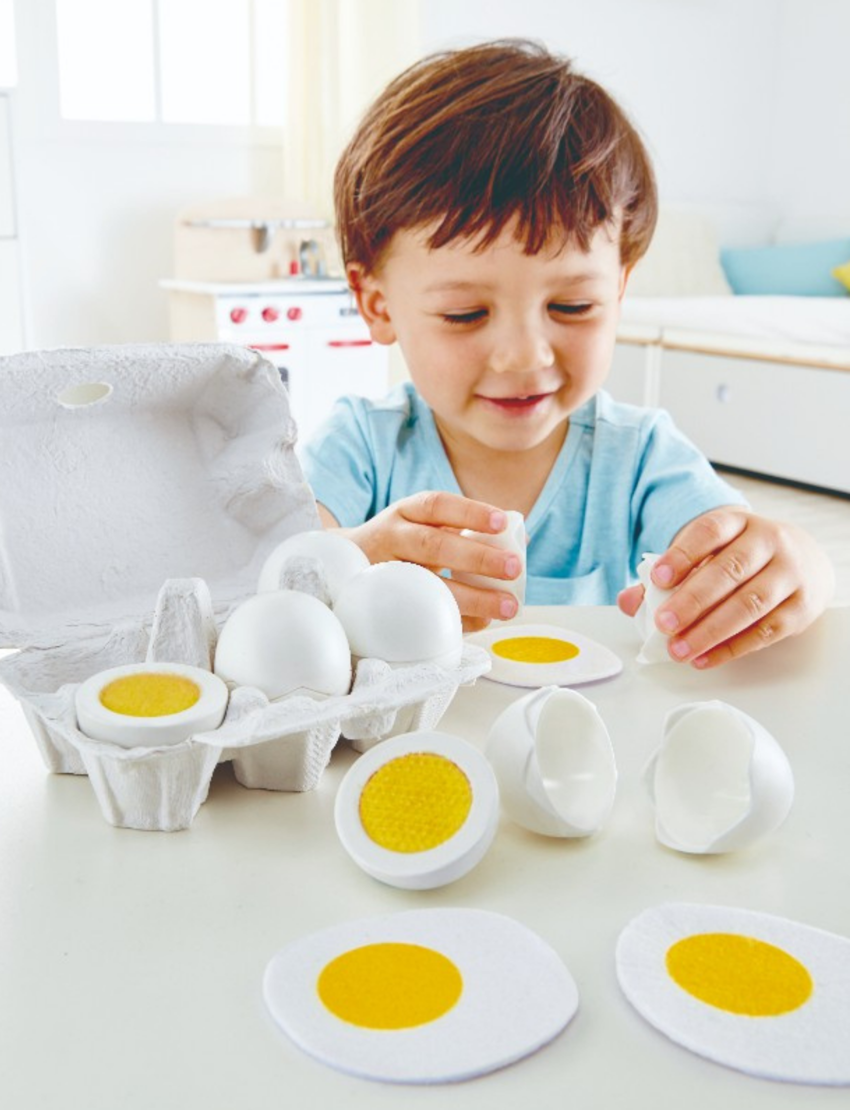 The Hape Egg Carton includes three whole white eggs, several halved eggs with yellow centers, one whole egg with the top removed, two empty shells, and a flat realistic play egg representation with a yellow center—making it an ideal addition to any kids' cooking set.