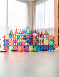 A box of the Connetix Tiles 212-Piece Magnetic Tile Mega Pack features red packaging adorned with images of vibrant geometric shapes creating a rainbow structure. The text states 