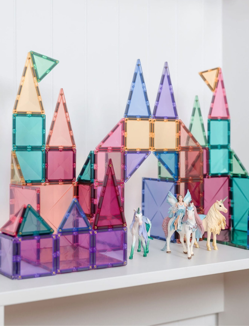 The image showcases a box of Connetix Tiles, specifically the Pastel Starter Pack 64-Piece. The purple packaging presents an assortment of vibrant geometric shapes in delightful pastel colors, designed to ignite creativity in children aged 3 and above.