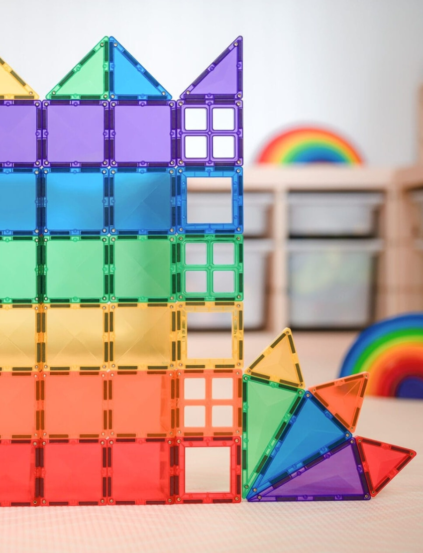 A package of Connetix Tiles Rainbow Starter Pack 60-Piece is shown, labeled accordingly. The box is adorned with vibrant geometric designs and images depicting an array of 2D and 3D structures that can be constructed with the tiles. It is suitable for ages 3 and up.