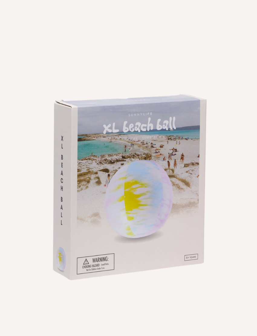 A product box for the Sunnylife XL Inflatable Beach Ball Tie Dye Sorbet, showcasing an image of the deflated beach ball against a coastal beach scene with people in the background. Warnings and product details are displayed on the lower portion of the box.