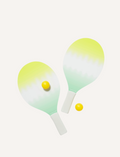 Two Sunnylife Beach Bats Sea Seeker Dip Dye with gradient green and yellow coloring and soft foam handles are placed beside two small yellow balls on a white background, making a perfect summer accessory.