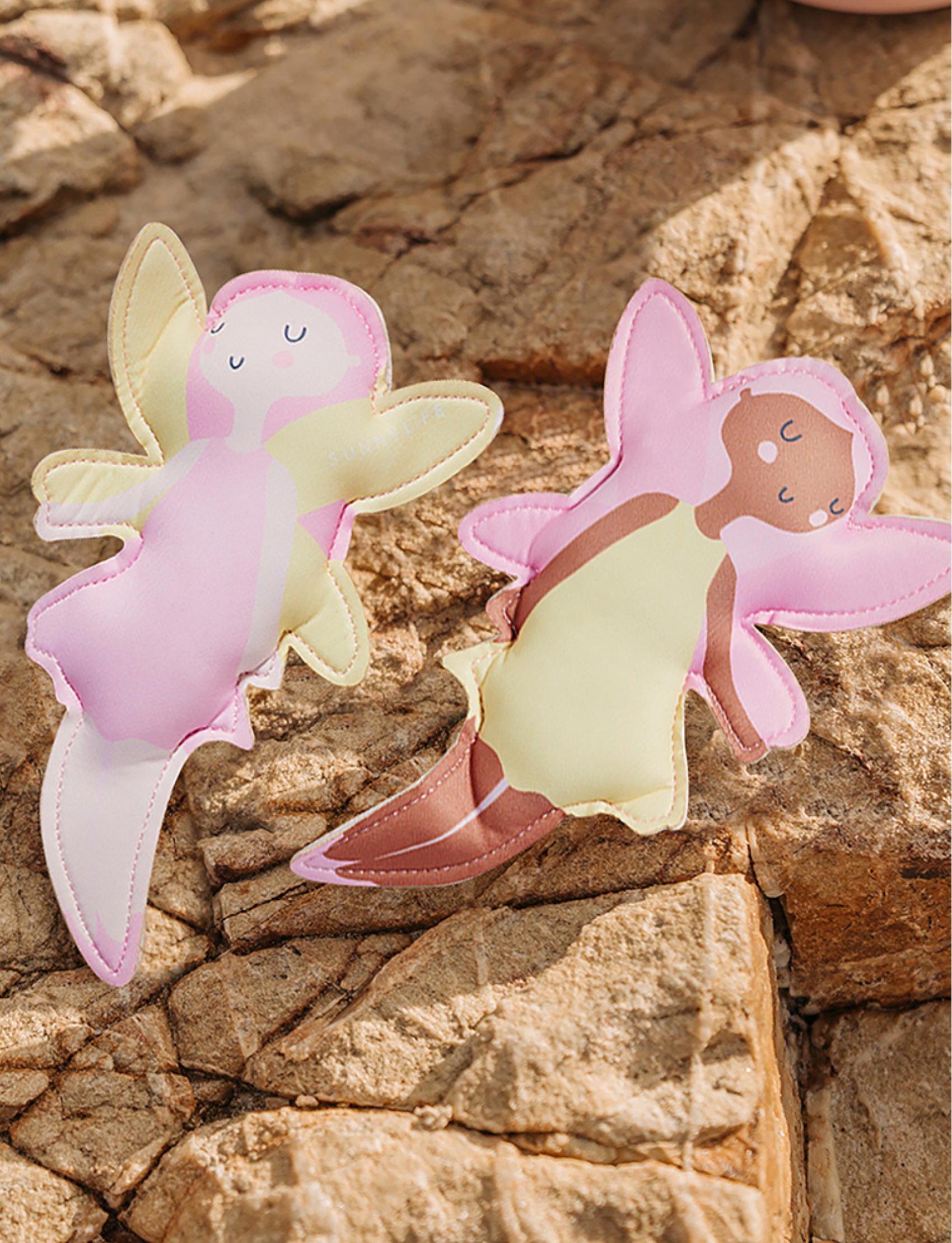 Three vibrant Dive Buddies Mima the Fairy Lemon Lilac toys from Sunnylife are arranged on a light background. These fairies, who resemble eye-catching diving toys, have wings and wear bright outfits in pastel colors including pink, yellow, and purple. Each fairy has a joyful smiling face.