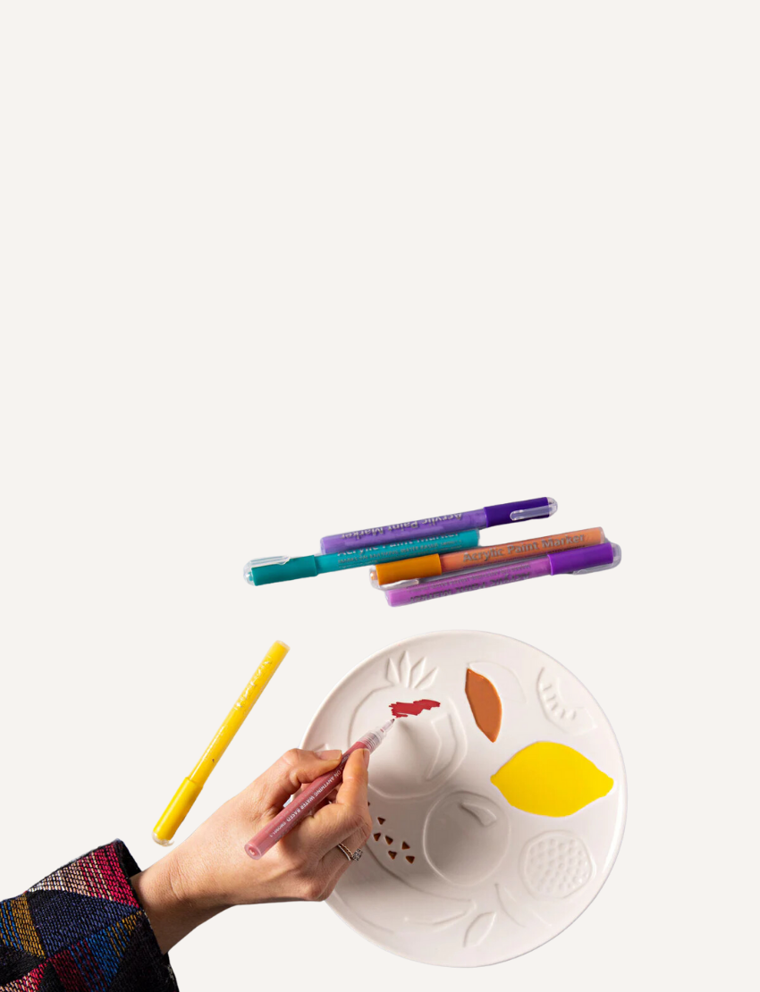 Image of the "Paint Your Own Plate - J.O.S Studio" by Journey of Something. The kit includes a plain ceramic plate with embossed leaf patterns, a set of colored markers, and a small palette. The packaging displays a partially colored plate as an example of the potential outcome.