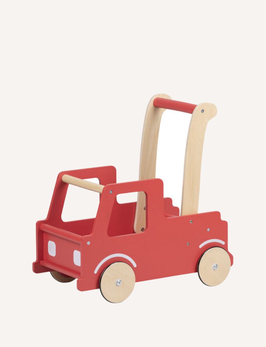 The Moover Push Truck is a red wooden toy car featuring beige wheels and handlebars. It boasts a simplistic design with cut-out windows and a small basket area at the back, marked with the word "LINE." This toy is designed for children to push or pull.